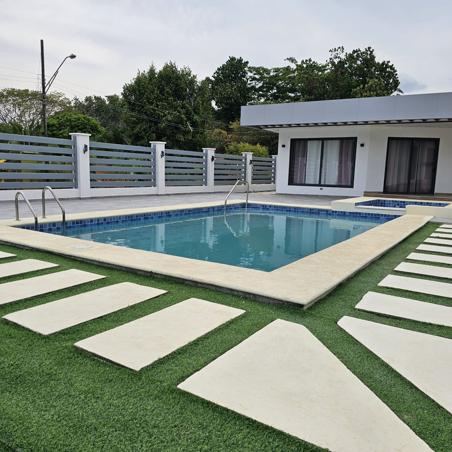 Piscina con jardín y adoquines decorativos