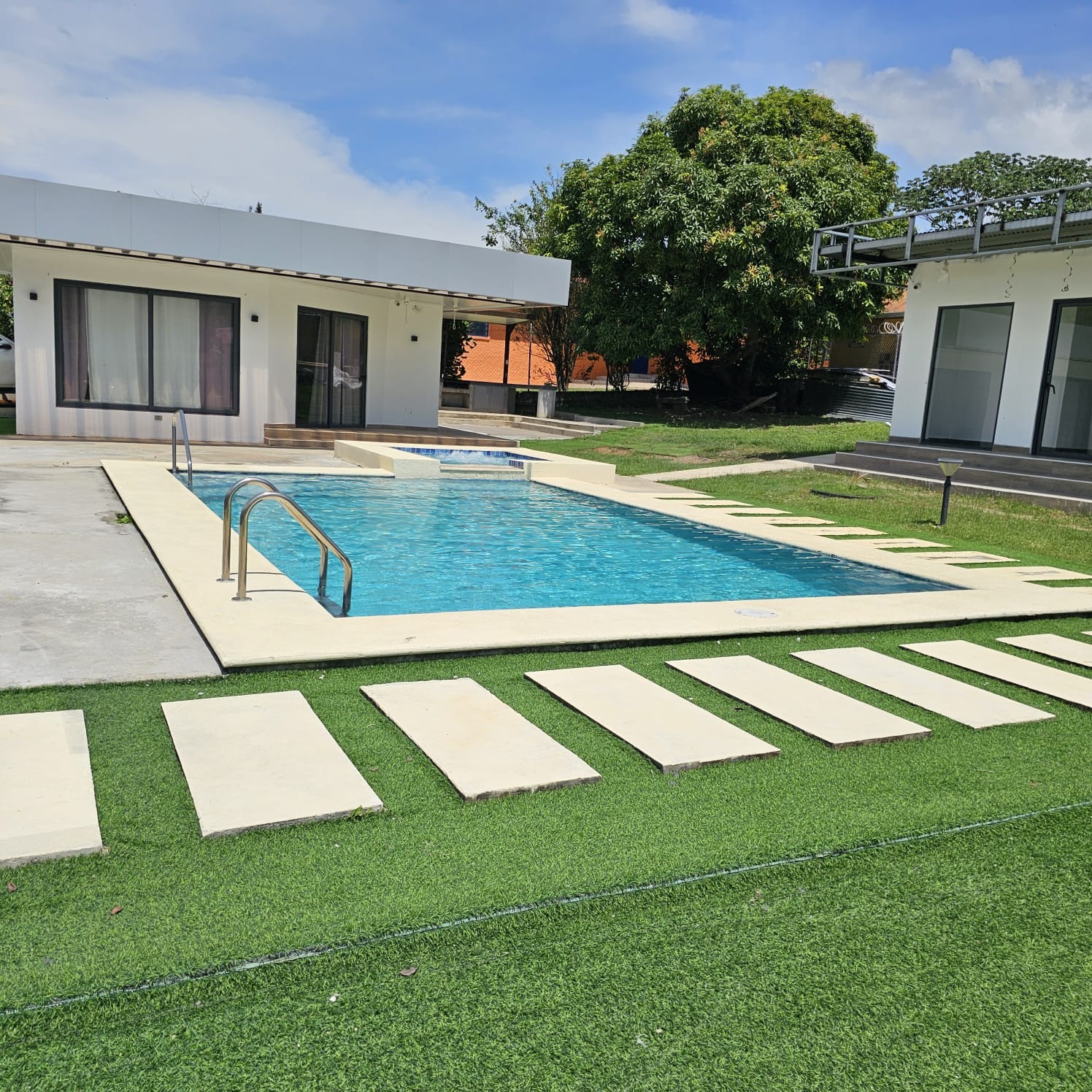 Piscina con césped artificial y stepping stones